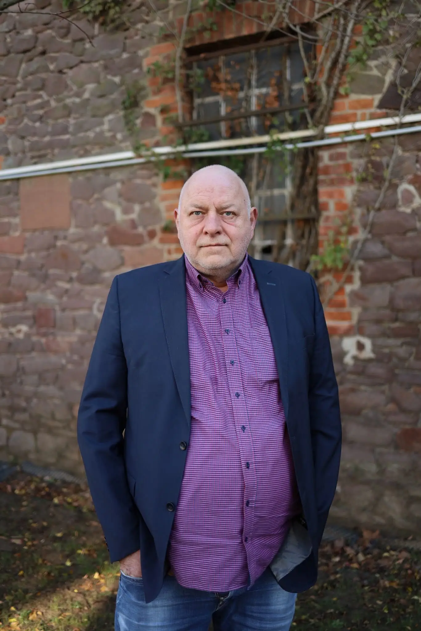 Holger Borchert stehend vor einer Mauer mit Fenster