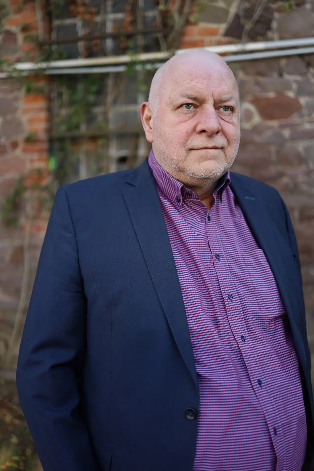 Holger Borchert im Sakko vor einer Steinmauer